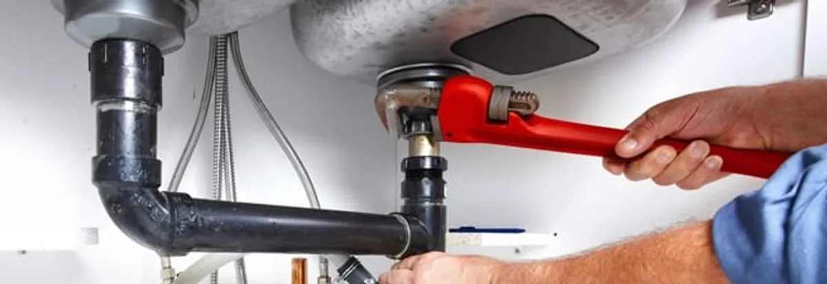 Garbage disposal repair technician tightening the sink drain and disposal connection in Anaheim, CA