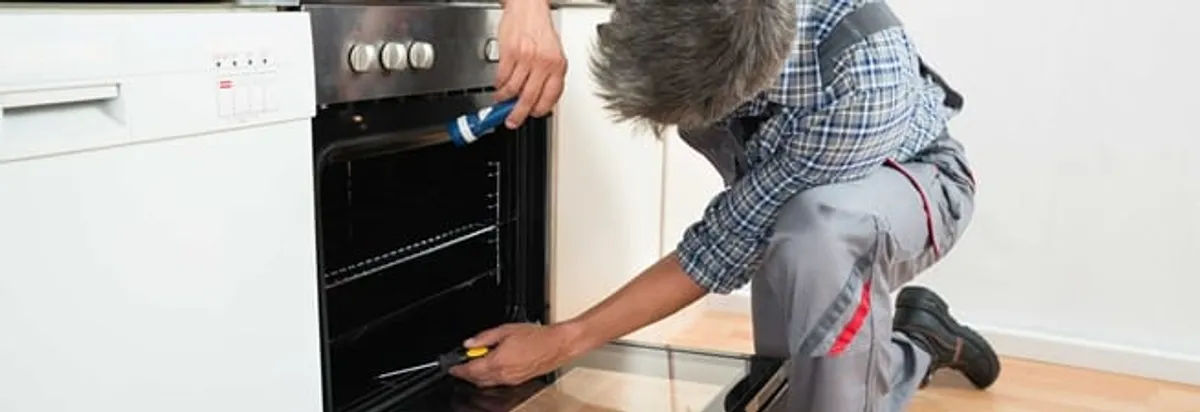 Oven repair technician inspecting and servicing an electric oven in Anaheim, CA