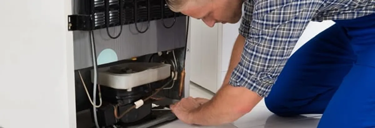 Refrigerator repair technician servicing the compressor and condenser area in Anaheim, CA