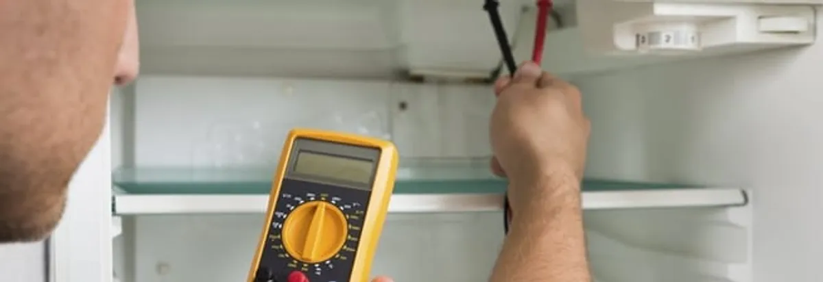 Refrigerator repair technician testing electrical components with a multimeter in Anaheim, CA