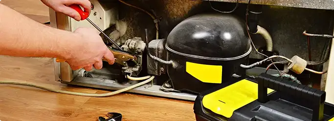Refrigerator repair technician fixing the compressor and wiring in Anaheim, CA